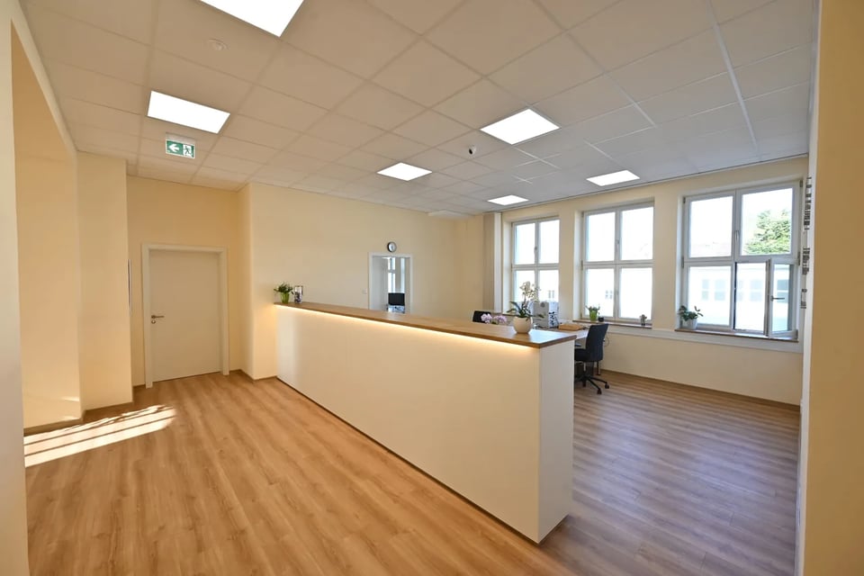 Anmeldung der Hausarztpraxis Schlitz mit langem hellem Tresen aus Holz, Arbeitsplatz und großen Fenstern im Alten Postamt