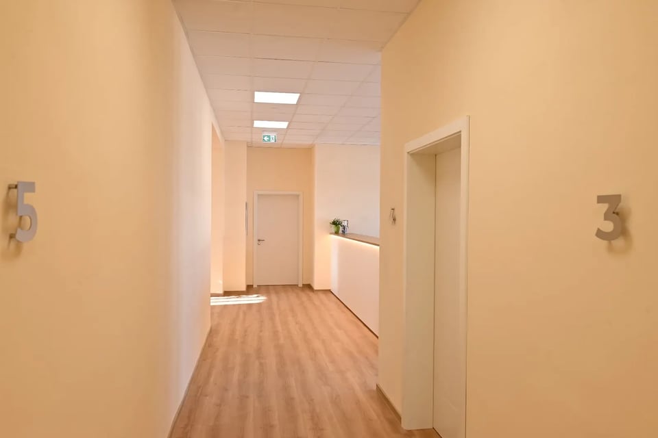Heller Flur der Hausarztpraxis Schlitz mit nummerierten Türen und Empfangsbereich im Alten Postamt