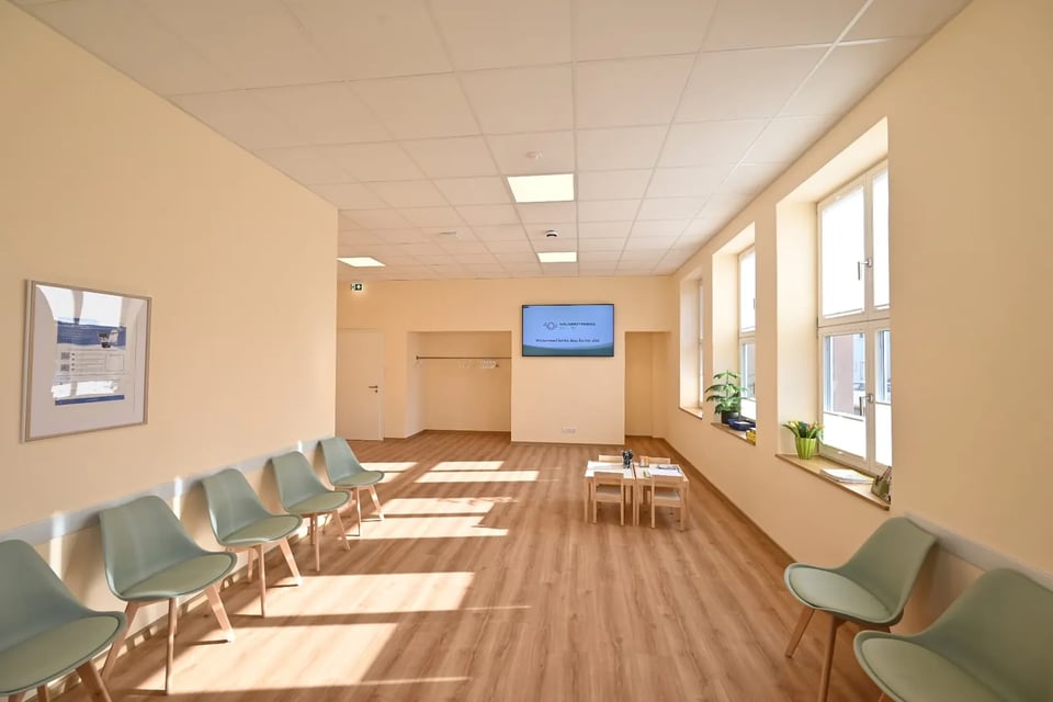 Helles Wartezimmer der Hausarztpraxis Schlitz mit Sitzgelegenheiten in Salbeigrün, Kinderbereich und großflächigen Fenstern im Alten Postamt